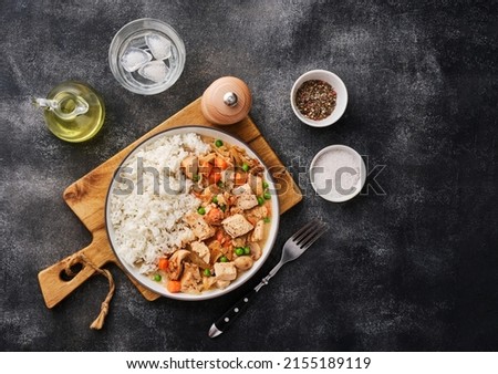 Chicken stew with vegetables and mushroom cream sauce. Tender chicken fillet in a creamy mushroom sauce with rice and green peas. Top view, flat lay.