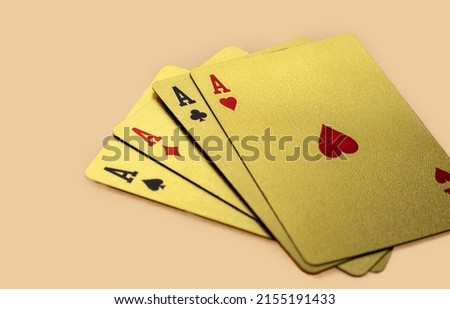 golden casino playing cards in a row or chaotic arrangement on orange background. four aces isolated, joker card on the top. Gold plated poker playing cards. luxury,waterproof