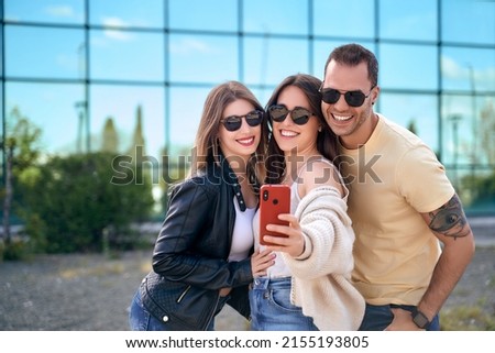 Group of teenage friends with sunglasses happily laughing and taking a selfie on the street. High quality photo