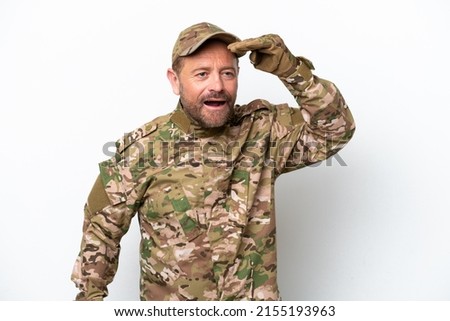Military man isolated on white background looking far away with hand to look something