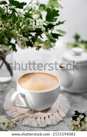 Cup coffee with milk and blooming tree brunches stillife image