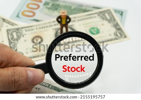 Preferred Stock.Magnifying glass showing the words.Background of banknotes and coins.basic concepts of finance.Business theme.Financial terms.