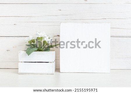 Mockup of a white wooden sign. White square sign on the table with a flower.