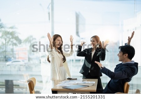 Young multiethnic diverse creative asian group huddle and high five hands together in office workshop with success or empower expression in teamwork. Young asian marketing team with copy space Royalty-Free Stock Photo #2155201331