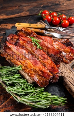 Roasted pork Bacon sizzling slices on wooden board. Wooden background. Top view. Royalty-Free Stock Photo #2155204411