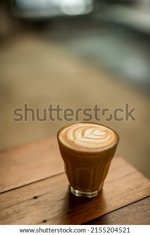 a cup of piccolo latte on wooden table 