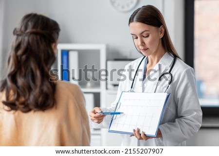 medicine, healthcare and people concept - female doctor or cardiologist with clipboard showing cardiogram to woman patient at hospital Royalty-Free Stock Photo #2155207907