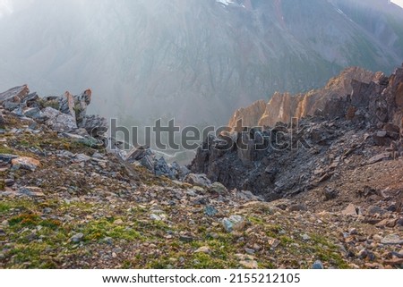 Awesome mountain view from cliff at very high altitude. Scenic landscape with beautiful sharp rocks near precipice and couloirs in sunlight. Beautiful mountain scenery on abyss edge with sharp stones. Royalty-Free Stock Photo #2155212105