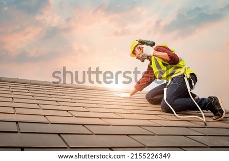Technician in shirt and jeans wear helmet safety suit

hand use screwdriver tool install repair C-Pack roof on high work place.Workers work at heights with full safety suits on construction sites. Royalty-Free Stock Photo #2155226349