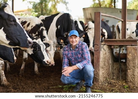 happy male farmer on cow farm around herd Royalty-Free Stock Photo #2155246775
