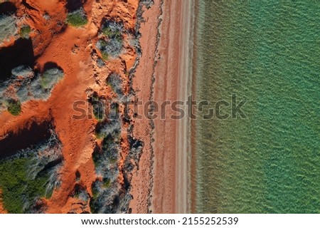 Aerial drone landscape view of coastal sea shore red cliffs and turquoise water environment at Peron Peninsula in Shark Bay, Western Australia. No people. Copy space
