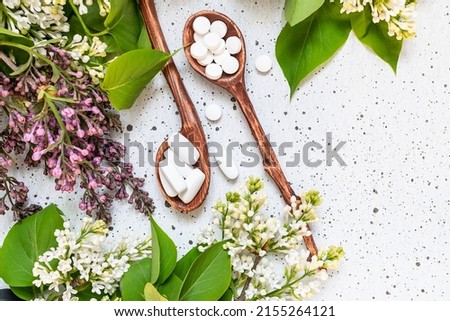 White medical tablets and pills on light marble background with aromatic lilac branches. Natural herbal medicine concept. Royalty-Free Stock Photo #2155264121