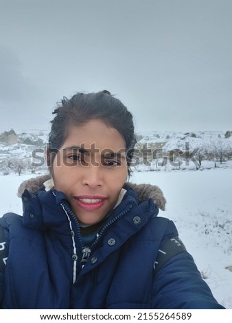 selfie of a young tan skin woman in the snow