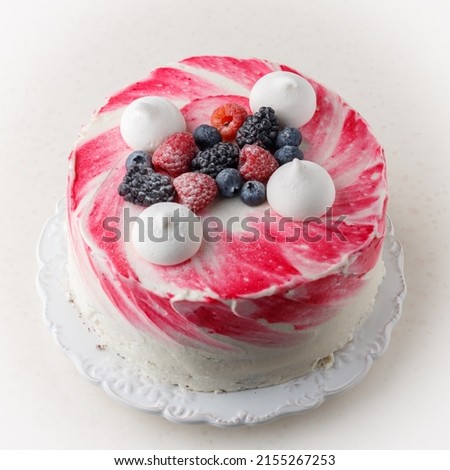 Homemade delicious mousse cake, glazed white chocolate, decorated with blueberries, raspberries, blackberries, meringue and powdered sugar. Berry cheesecake. Healthy dessert. Square picture, close-up
