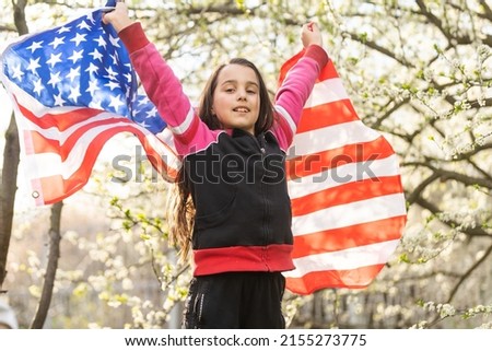 Happy adorable little girl smiling and waving American flag. Patriotic holiday. Happy kid, cute little child girl with American flag. USA celebrate 4th of July. Independence Day concept.