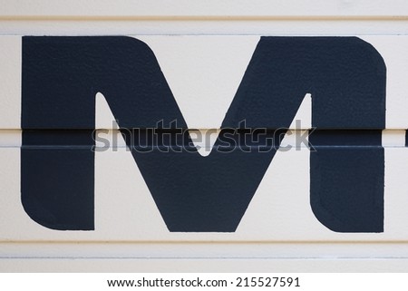 black uppercase letter M painted on garage door