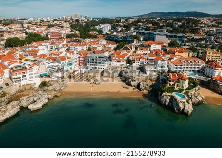 Drone aerial view of unidentifiable sunbathers at Praia da Rainha beach in Cascais, Portugal, a popular summer vacation spot for Portuguese and foreign tourists Royalty-Free Stock Photo #2155278933