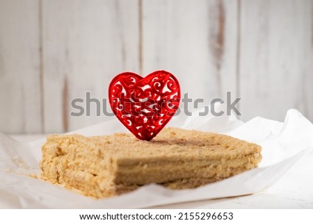 Cake with a red heart. Vegetarian napoleon cake with valentine's day decor. Minimalistic design. White background.