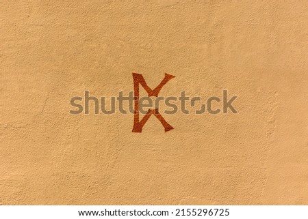 shot of a runic letter drawn on a yellow wall, the specific rune is Perthro