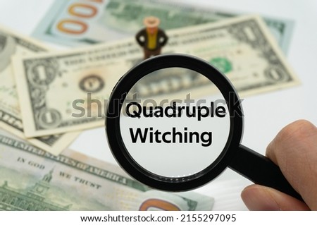 Quadruple Witching.Magnifying glass showing the words.Background of banknotes and coins.basic concepts of finance.Business theme.Financial terms. Royalty-Free Stock Photo #2155297095