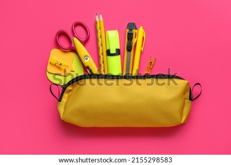 Yellow pencil case with stationery supplies on pink background Royalty-Free Stock Photo #2155298583