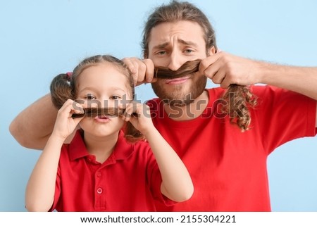 Funny man and her little daughter on blue background. April fools' day celebration
