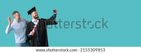 Happy male graduation student and his father taking selfie on blue background with space for text