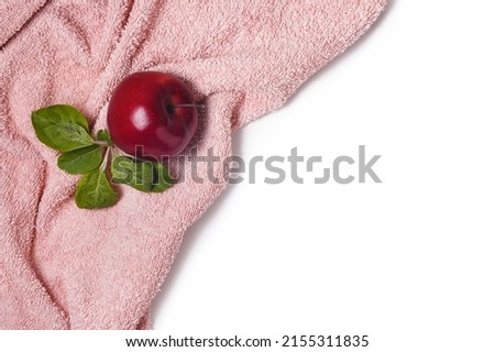 Top vief of red apple with green leaves on fur pink towel on white, copy space, flat lay.