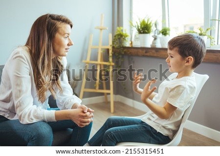 Young female psychologist working with little boy in office. Shot of a young child psychologist talking with a boy. Young female school psychologist having serious conversation with smart little boy