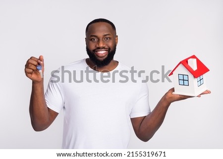 Photo of cute funny guy dressed casual t-shirt holding hands red roof house keys isolated white color background