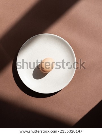 Still life with an egg on a plate. Photos in natural colors. Minimal food concept. Dramatic light and shadows