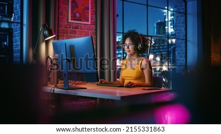 Young Multiethnic Woman in Chatting on Video Call on Computer in Stylish Loft Apartment in the Evening. Happy Creative Female Working from Home, Talking to Client Support or Family and Friends. Royalty-Free Stock Photo #2155331863