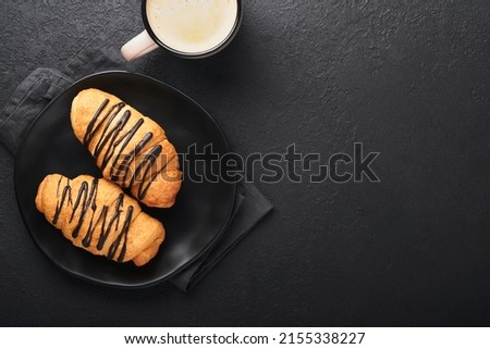 Coffee and croissant. Espresso coffee and croissant with chocolate on old on black concrete table. Perfect Croissant Breakfast in the morning. Rustic style. Top view. Mock up.