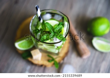Close up shot of a mojito cocktail with fresh peppermint and lime on a wood table, summer drink.