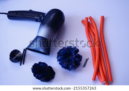 Close up shot of hair accessories curler sticks, dryer, pins and rubber bands on a white background.