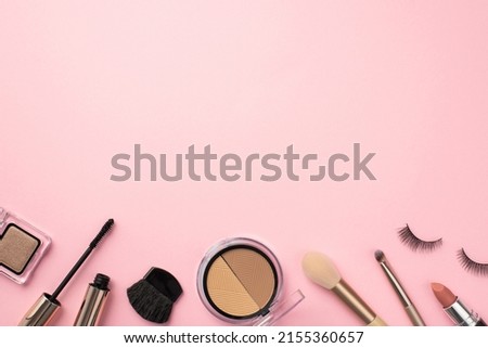 Make-up concept. Top view photo of contouring palette lipstick false eyelashes makeup brushes mascara and eyeshadow on pastel pink background with copyspace