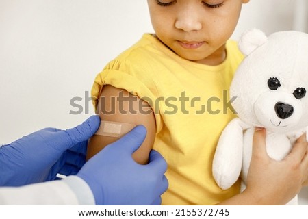Doctor stick a band-aid on a girl's shoulder after a vaccination Royalty-Free Stock Photo #2155372745