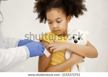 Male doctor stick a band-aid on a girl's shoulder after a vaccination Royalty-Free Stock Photo #2155372751