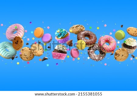 Cakes, sweets, confectionery mix background. Donuts, cookies cupcakes macaroons levitation over blue background
