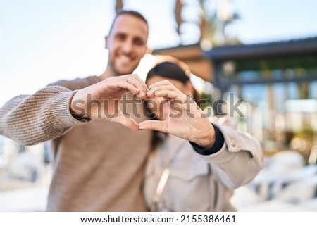 Man and woman smiling confident doing heart symbol with hands at street