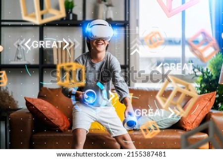 exiting asian child male boy enjoy metaverse gaming with wearable vr headset with control handle playing sport gaming online in living room at home,home technology young teen using vr technology Royalty-Free Stock Photo #2155387481