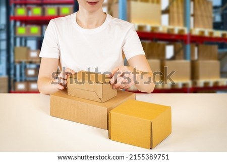 Work in the warehouse. Product packaging. Delivery of goods. Warehouse and delivery business. A woman packs goods in a cardboard box on the background of a warehouse. Storekeeper and cardboard boxes.