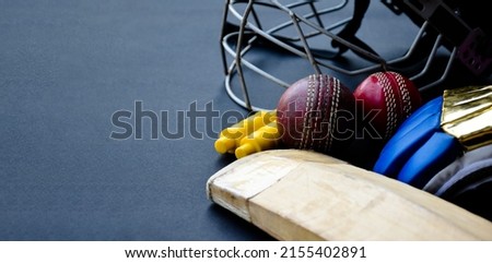 Training cricket sport equipments, bat, ball, gloves, wickets, and helmet, on dark floor, concept for cricket sport lovers all over the world.