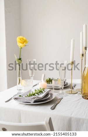 beautiful table setting for romantic dinner for two, with Linen napkins , yellow rose and boxwood. Close up