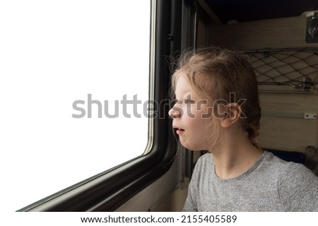 the girl looks out the train window with surprise. White window with a place for a picture