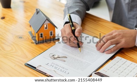 Businessmen holding pens, signing home titles with insurance, care about real estate services and the idea of real estate agents offering interest in installments to their customers. Royalty-Free Stock Photo #2155408449