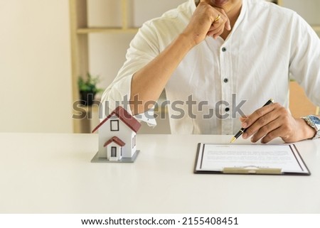Businessmen holding pens, signing home titles with insurance, care about real estate services and the idea of real estate agents offering interest in installments to their customers. Royalty-Free Stock Photo #2155408451