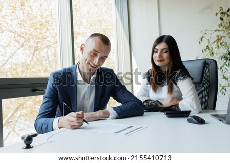Business man and woman signing a contract smiling business persons making an agreement