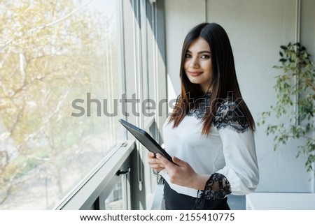 Business woman with a tablet working from an office Young handsome woman administrating a business Royalty-Free Stock Photo #2155410775