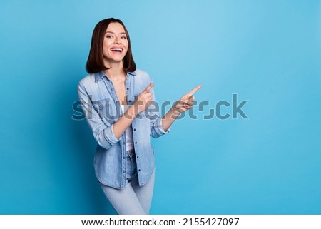 Photo of shiny excited woman wear jeans shirt smiling pointing empty space isolated blue color background